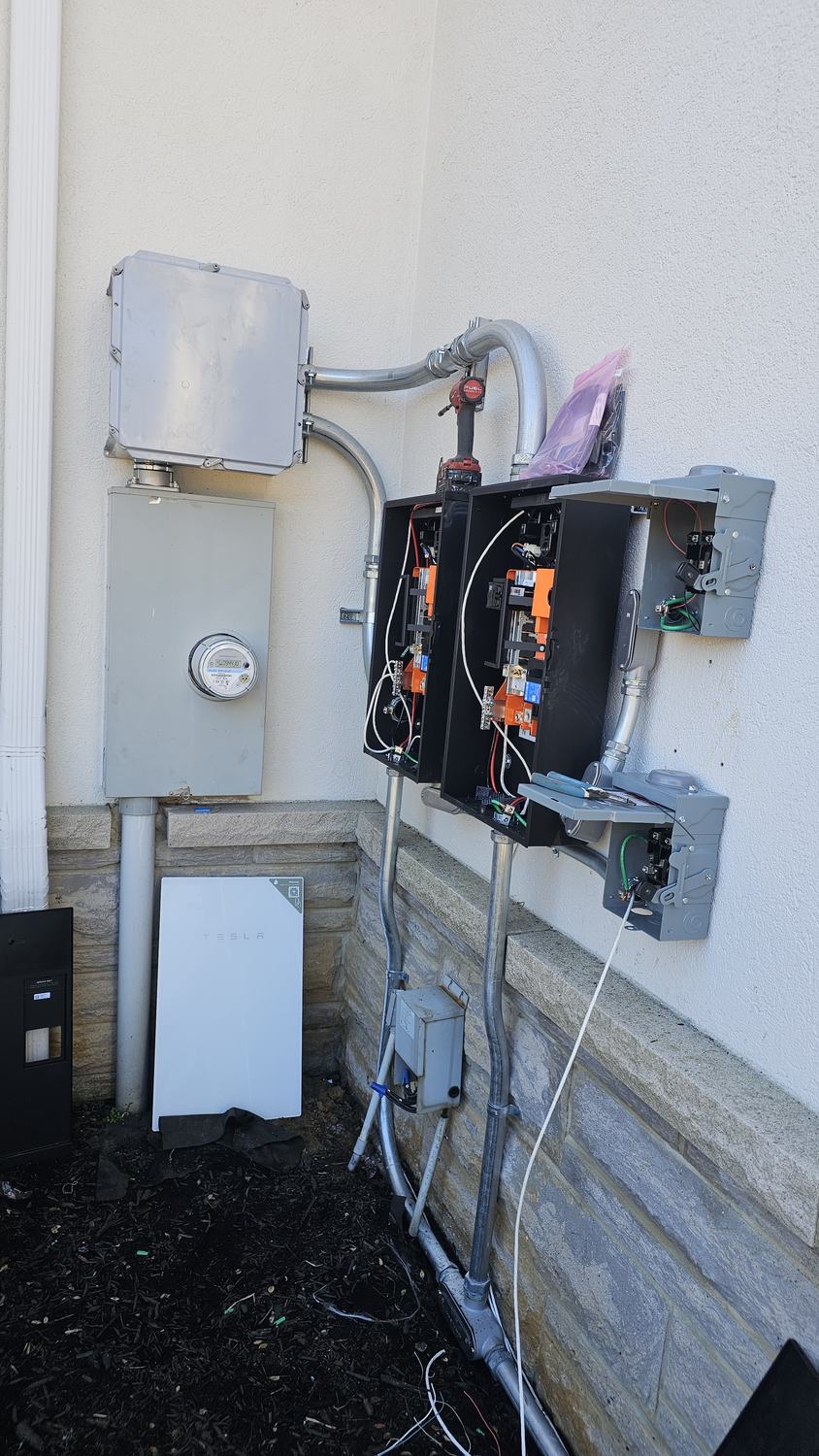 Tesla Powerwall and energy management equipment mounted on an exterior wall