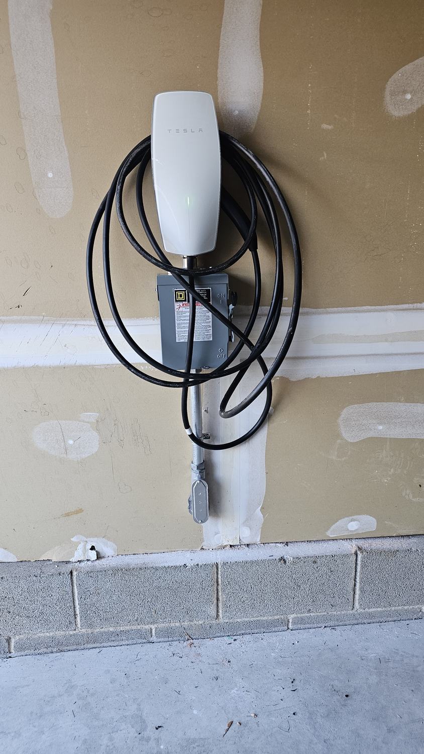 Tesla Wall Connector EV charger mounted on garage wall